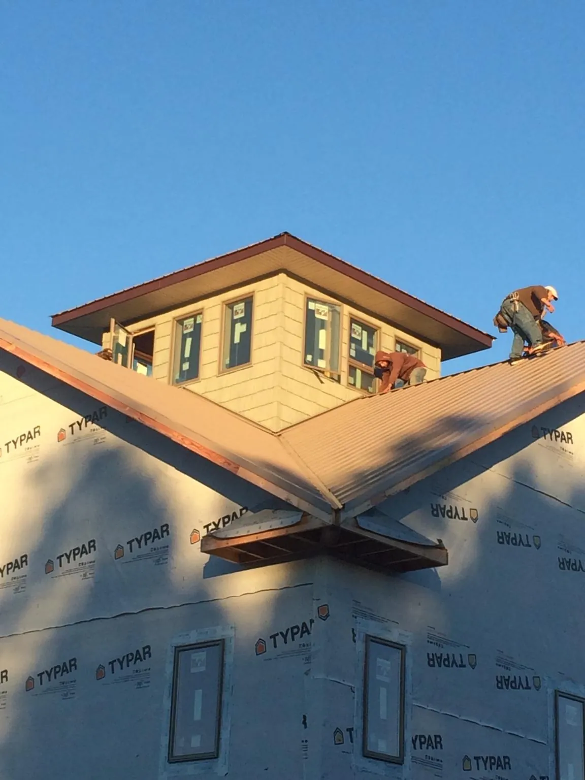 Roofers working around a rooftop cupola on a new metal roof at sunset — Roof Waterproofing in Pulaski by Roofing Brothers